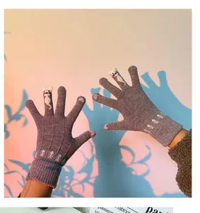 Close-up detail of cute winter knit cat gloves for women, warm touch screen five-finger design.