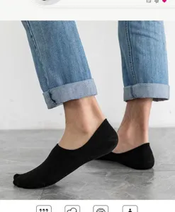 Detailed view of men's solid black low-cut invisible socks worn with jeans on floor.