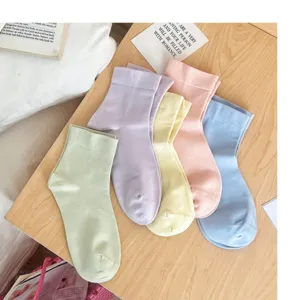 Close-up detail of pastel women mid-tube socks in vibrant soft colors on wooden table.