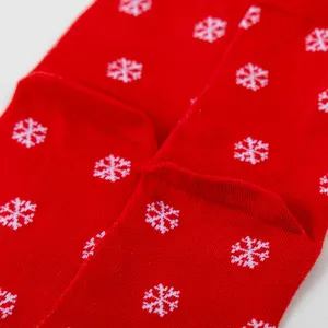 Red Christmas winter knit socks detail close up showing white snowflake pattern fabric.