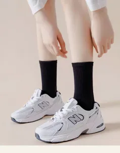 Detailed close-up view of black cotton mid-tube socks worn with casual sneakers.