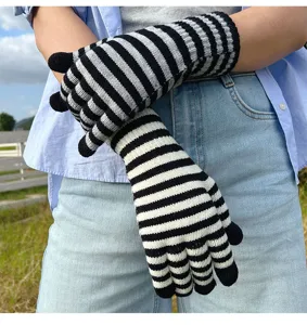Detail view of black and white striped knit gloves, showing the texture and fingerless design.