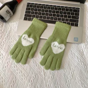 Close-up van groene gebreide touchscreen handschoenen met wit hart en love patroon.