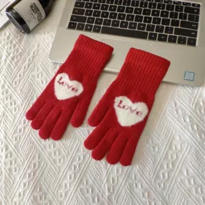 Gedetailleerd overzicht van rode gebreide handschoenen met wit hart en liefdespatroon.