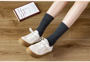 Detail shot of solid dark grey mid-calf loop pile cotton socks worn on wooden floor.