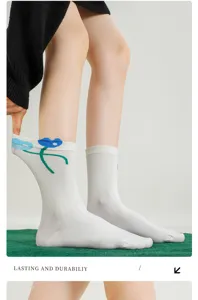 Close-up detail of white crew socks featuring cute blue and green cartoon flower patterns.