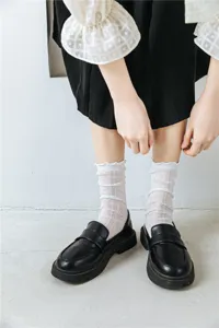 Primo piano dettagliato di eleganti calzini bianchi a rete con volant abbinati a scarpe nere.
