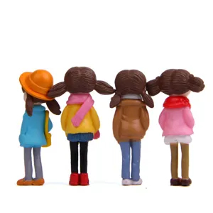 Close-up of cute miniature winter girl figurines with scarves, perfect for micro-landscape.