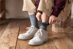 Detailansicht dicker thermischer Wintersocken kombiniert mit Stiefeln, kuschelige Wollmischung.