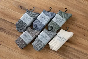 Detaillierte Nahaufnahme von dicken, melierten Strick-Wintersocken ordentlich auf Holz.
