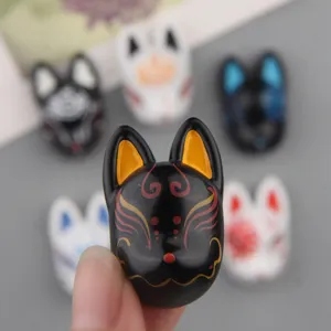 Close-up detail view of the resin Japanese fox mask miniature, showing fine painted patterns clearly.