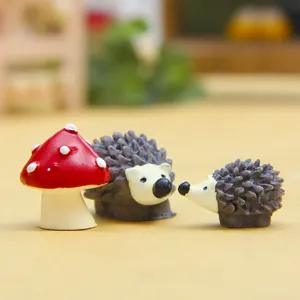 Nahaufnahme von niedlichen Miniatur Harz Igel und Pilz Figuren fuer Sukkulenten Dekoration.