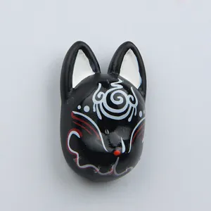 Detail shot of black resin Japanese fox mask fridge magnet, unique traditional painted pattern.
