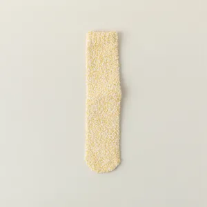 Détail en gros plan de chaussettes de sommeil duveteuses jaunes, texture polaire corail douce et chaude.