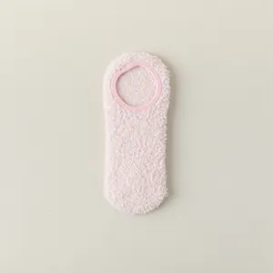 Primo piano dettaglio di calzini pantofola rosa soffici e spessi per la casa invernale.