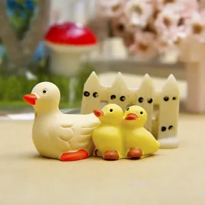 Nahaufnahme süßer gelber Miniatur-Harz-Entenfiguren mit kleiner Zaun-Deko für Mikrolandschaft.