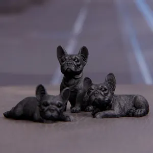 Primo piano dettagliato di tre statuette di bulldog francese nero per decorazione auto.