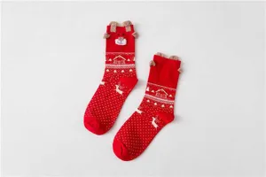 Close-up of red Christmas socks featuring 3D plush deer ears and festive knit pattern details.