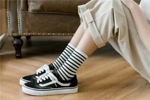 Close-up detail of women's black and white striped crew socks paired with casual canvas shoes.