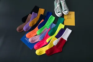 Detailansicht bunter Rippstrick-Baumwollsocken in Wadenlänge auf dunklem Grund mit Requisiten.