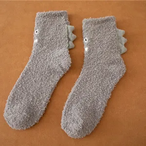 Dettaglio calzini in pile corallo grigio con simpatico design a spina di dinosauro e ricamo.