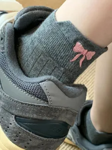 Close-up detail of gray cotton socks featuring a sweet pink embroidered bow design.