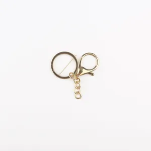 Dettaglio accessorio portachiavi in metallo dorato, con moschettone e anello brisè.