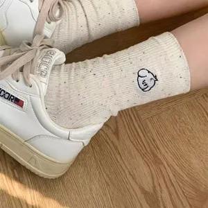 Close-up of white speckled crew socks with cute embroidered animal design, breathable and trendy.