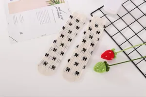 Detailed shot of cute white mesh crew socks with black bows, sweet balletcore style hosiery.