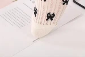 Close-up detail of sheer mesh lace crew socks featuring cute black bow pattern design.
