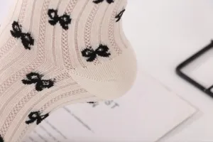 Close-up detail of women knit socks featuring cute black bows, hollow mesh summer style.