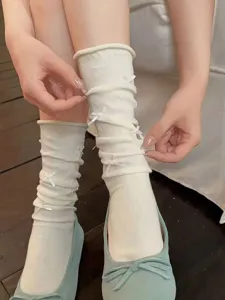 Detailed close-up of cute Japanese style white mid-tube stacked socks featuring sweet little bows.