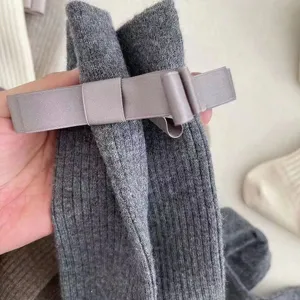 Primo piano dettagliato di calzini grigi a coste con un elegante fiocco in raso.