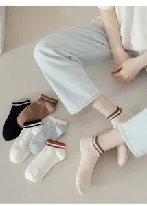 Detail shot of women's short striped boat socks in various colors worn on floor setting.