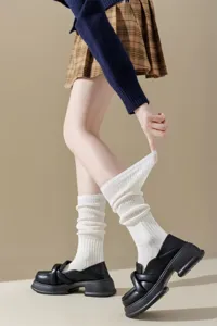 Close-up detail of women's white slouch socks with vertical ribbed knit texture and design.