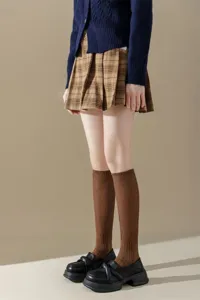 Detail view of brown ribbed knee-high socks paired with a stylish plaid pleated skirt.