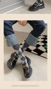 Argyle mid-calf socks paired with stylish classic black loafers and cuffed denim jeans.