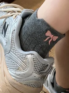 Close-up detail of women's grey ribbed socks featuring cute pink bow embroidery design.