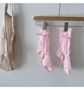 Gros plan détaillé de chaussettes mi-mollet roses style ballet avec de jolis nœuds.