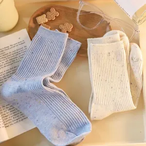 Detailed shot of pastel knit mid-calf socks with colorful speckles on cozy tabletop.
