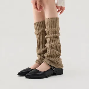Close-up detail of ribbed knit leg warmers in khaki, styled with black shoes for a chic look.