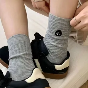 Detailed shot of grey ribbed knit mid-calf socks featuring cute black cat embroidery design.