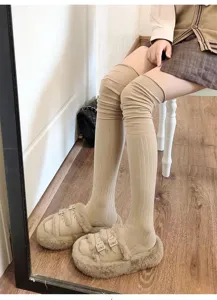Close-up detail of cozy ribbed over-the-knee knit socks in beige, perfect for stylish autumn wear.