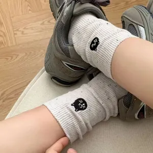 Detail view of cute speckled mid-calf socks with black cat embroidery worn with sneakers.