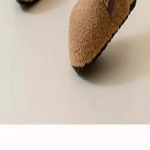 Close-up detail shot of cozy fuzzy brown slip-on clog shoe featuring metal buckle.