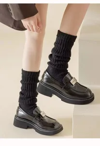 Detailed close-up view of black ribbed knit leg warmers paired with stylish platform loafers.