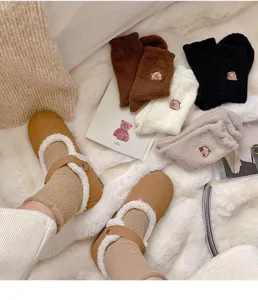 Cozy winter plush socks detail shot, thick fuzzy material with cute bear embroidery texture.