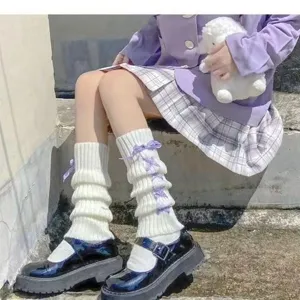 Close-up of white knitted leg warmers featuring cute purple ribbon lace-up design for cute style.