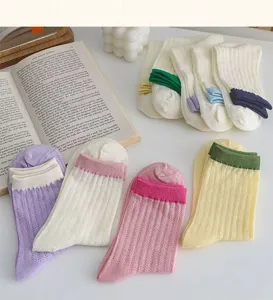 Detail shot of cute Japanese style candy colored mesh hollow mid-calf socks with colorful cuffs.