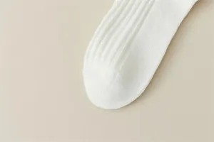 Close-up detail of white ribbed knit socks, showcasing fine texture and soft fabric material.